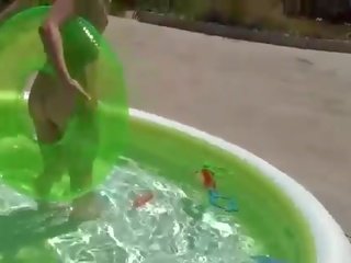 Playful rubia adolescente en bikini tiras y se burla en la piscina
